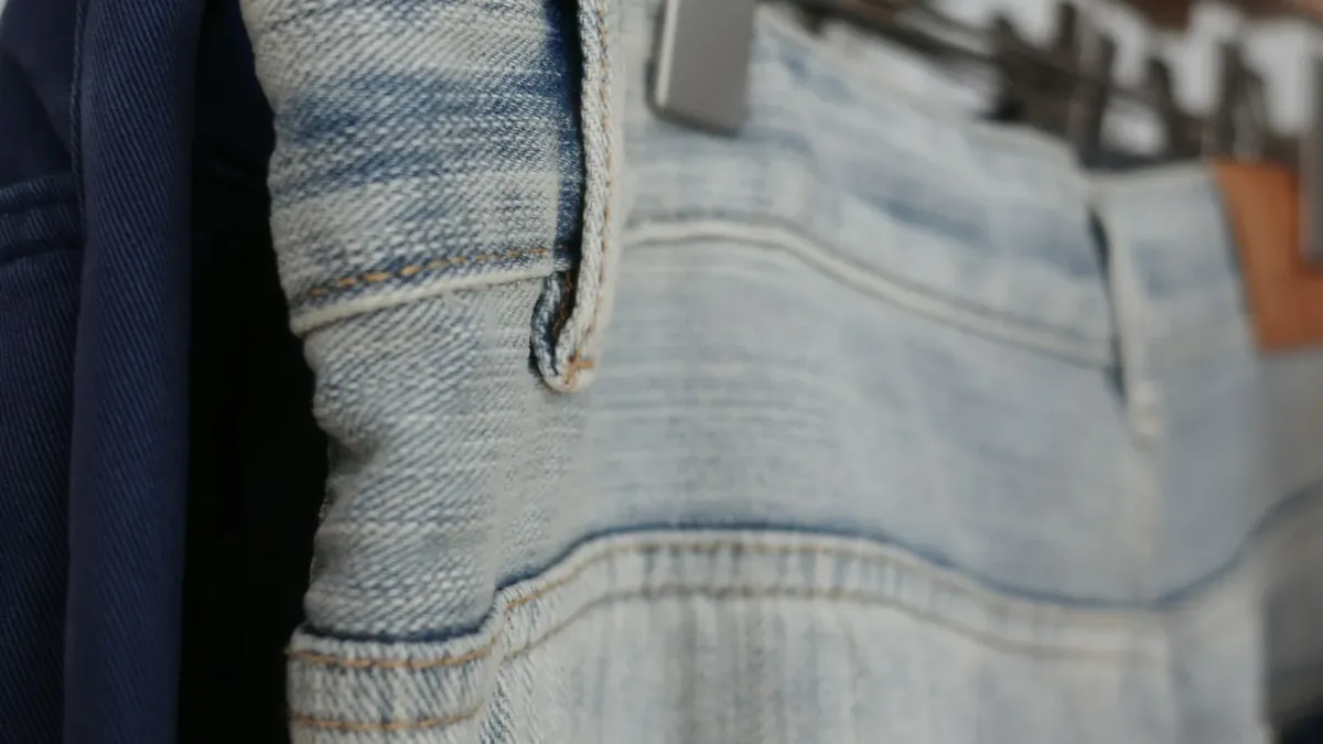 Light blue denim jeans hanging on a wooden hanger