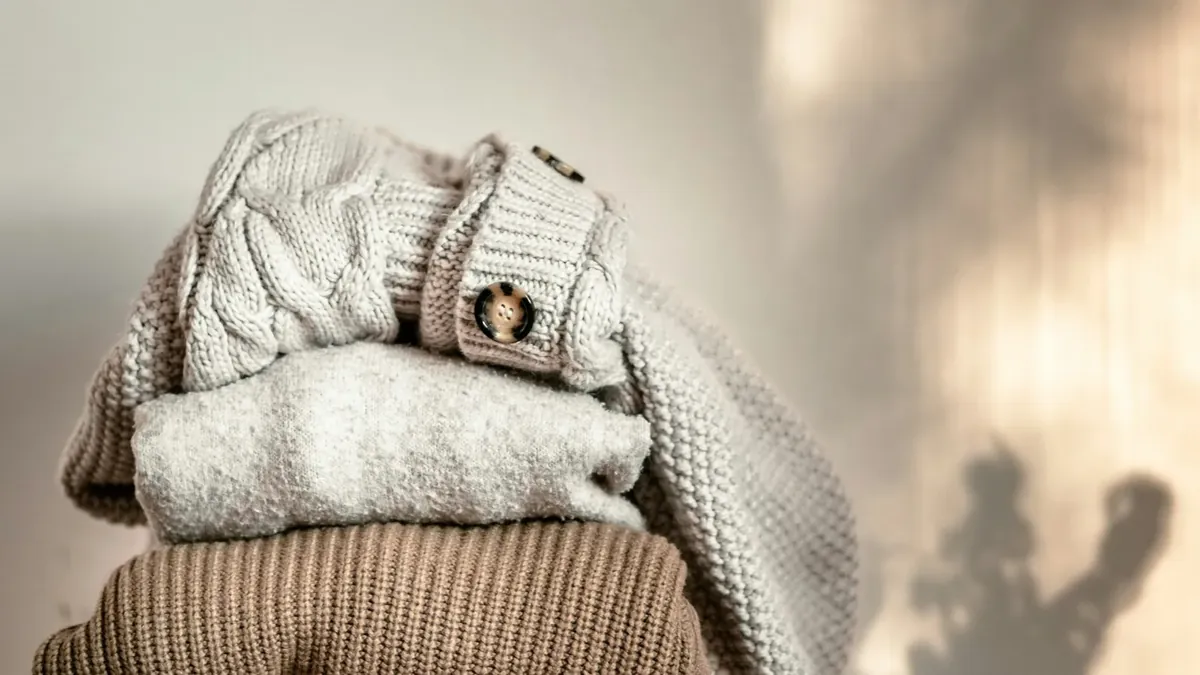 A stack of sweaters sitting on top of a wooden chair