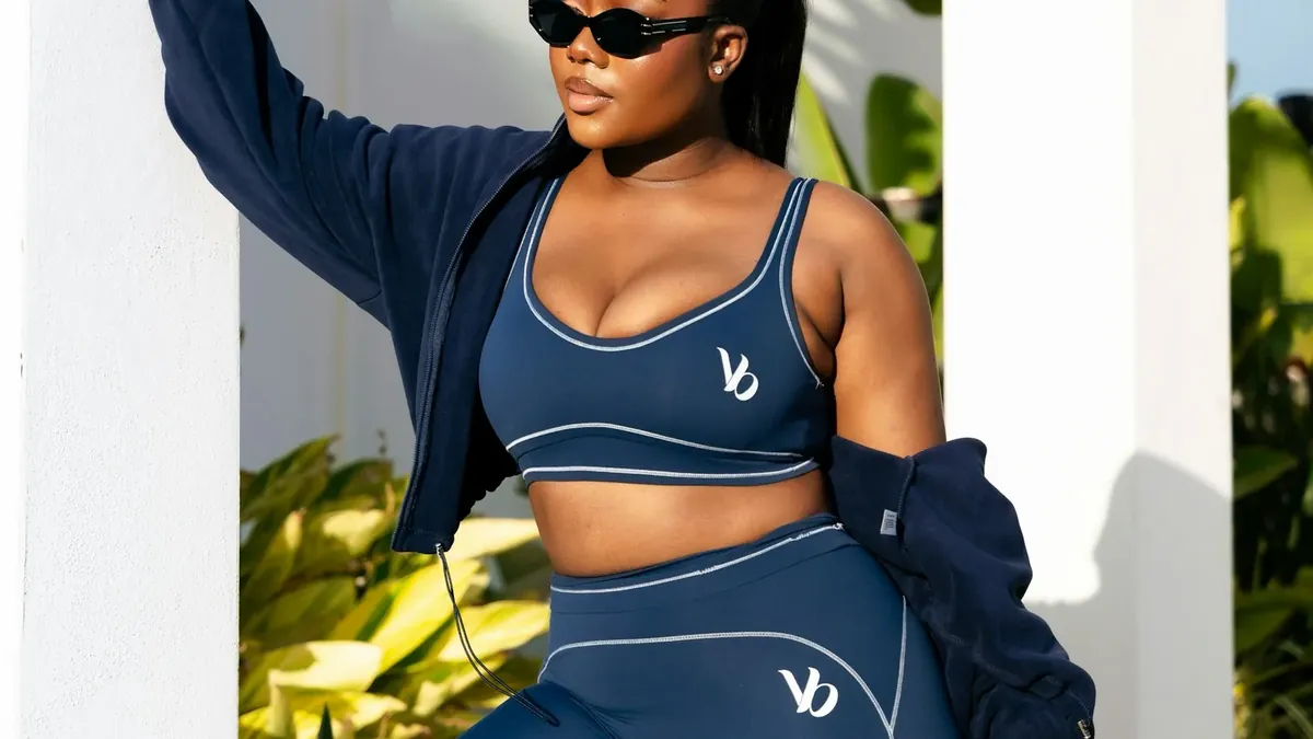 A woman in navy activewear holds a pink gym bag