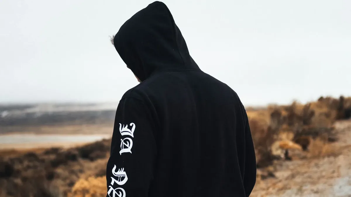 Person in black and white hoodie standing on brown field during daytime