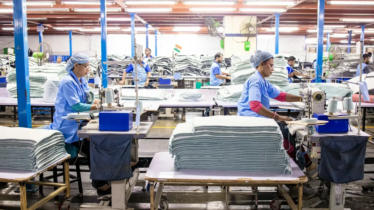 Workers sew textiles in a large factory setting