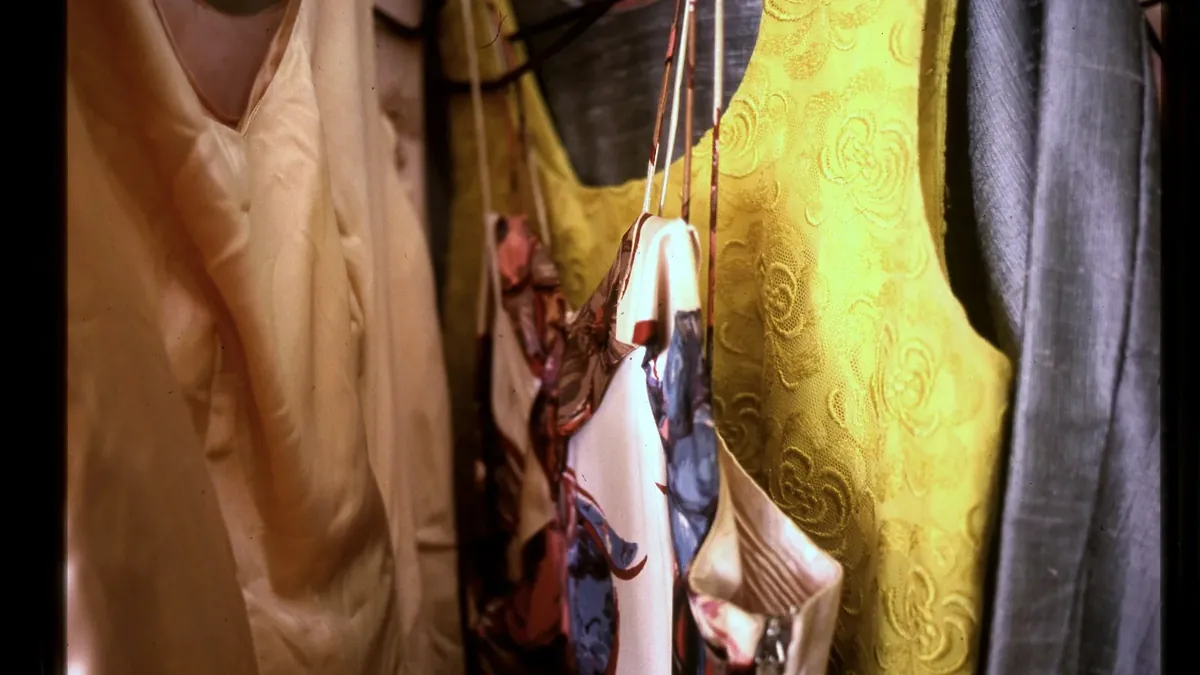 Various colorful clothes and patterned scarves hanging in a closet