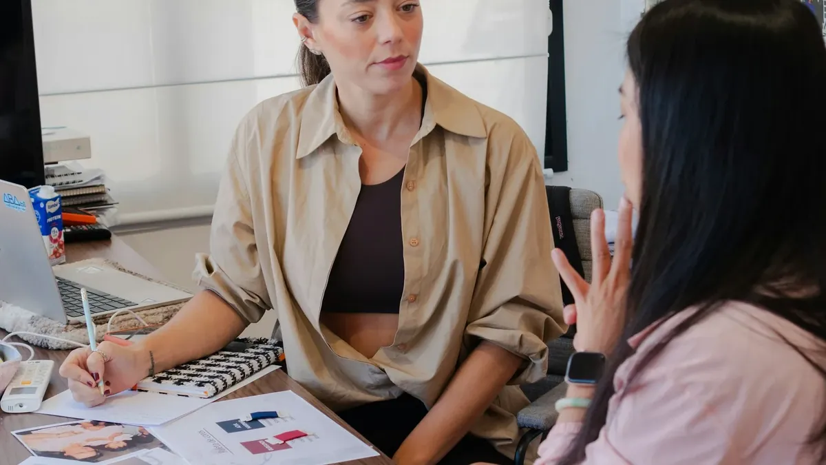 Two women collaborating at a desk with design materials
