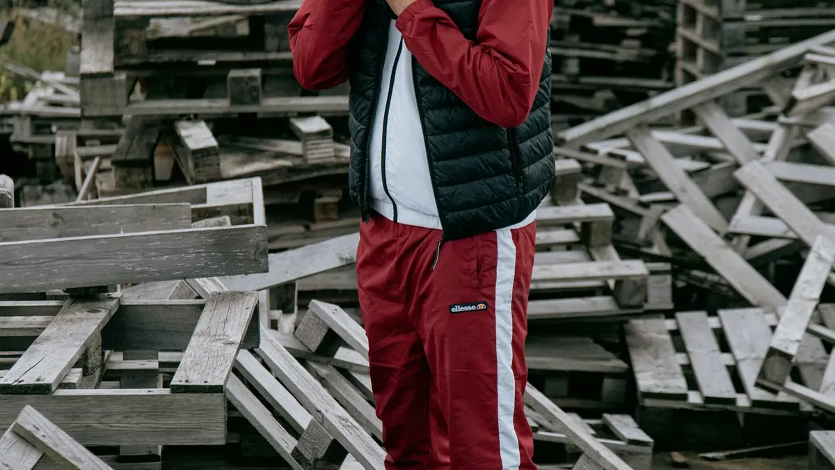 Man in black jacket and red pants standing on wooden stairs