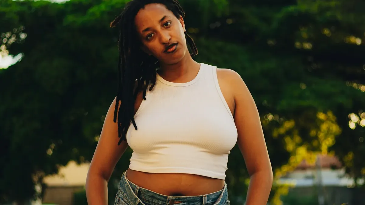 Young woman in white tank top and denim overalls