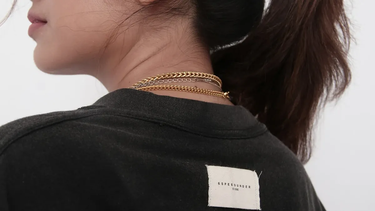 Person from behind wearing a black shirt and gold necklace