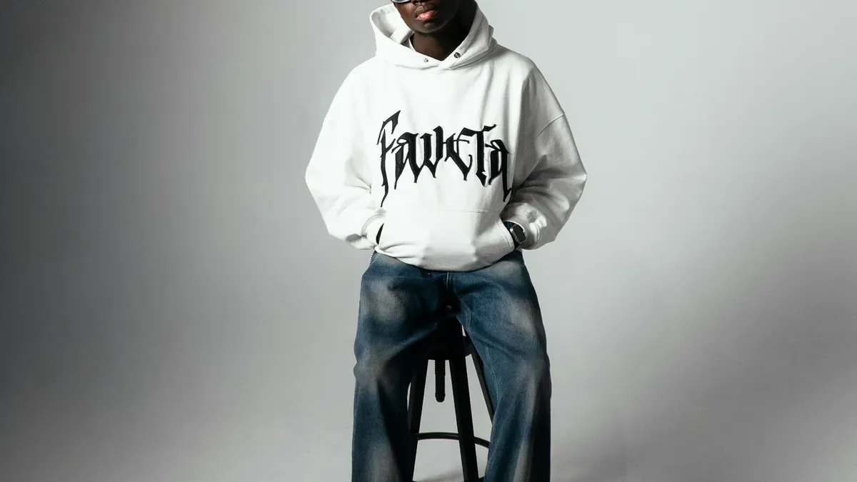 Young black man in white hoodie and jeans sitting