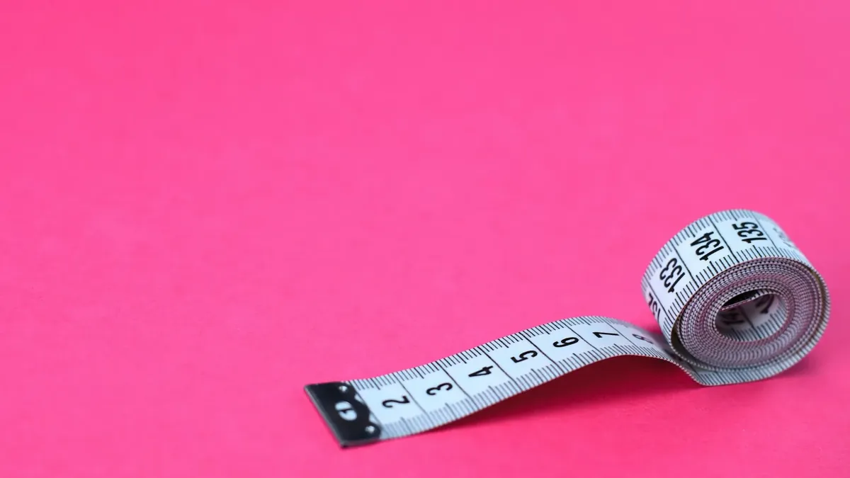 A measuring tape on a pink background
