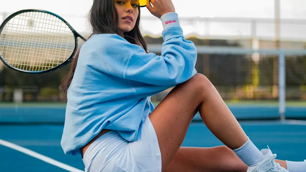 Woman in blue dress sitting on tennis court