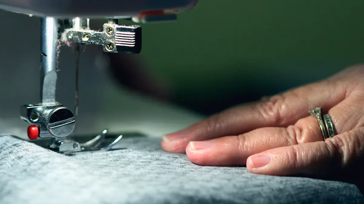 Person in gray shirt sewing