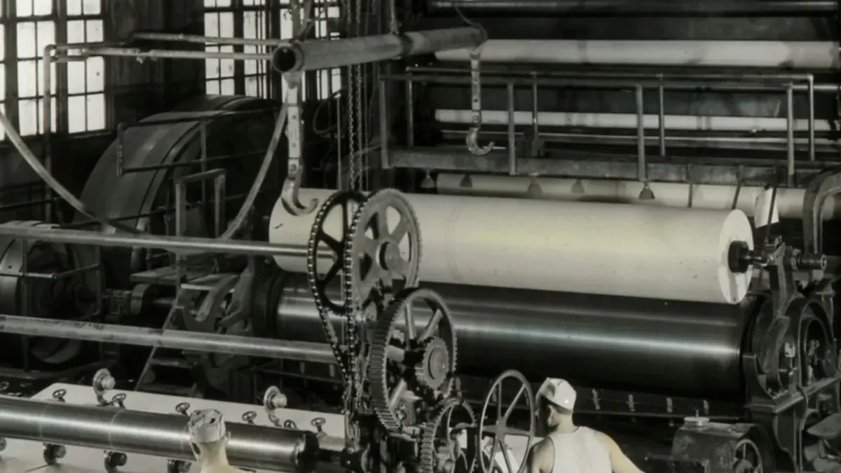 Workers operate large machinery in a factory setting