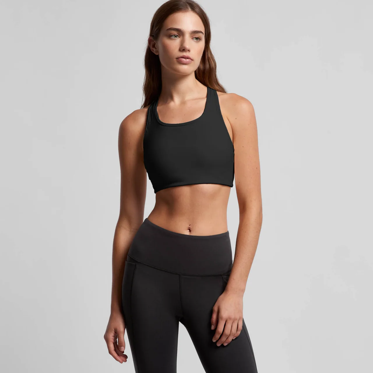 A model wearing a plain black sports bra and matching black leggings.