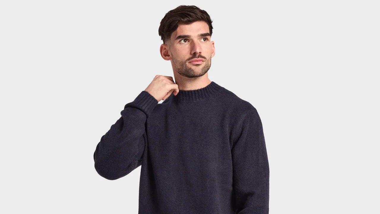 A model wearing a plain navy knitted crewneck top.