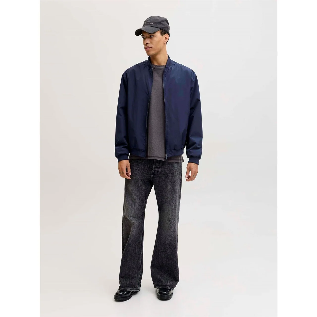 A model wearing a plain navy zip-front bomber jacket and dark trousers.