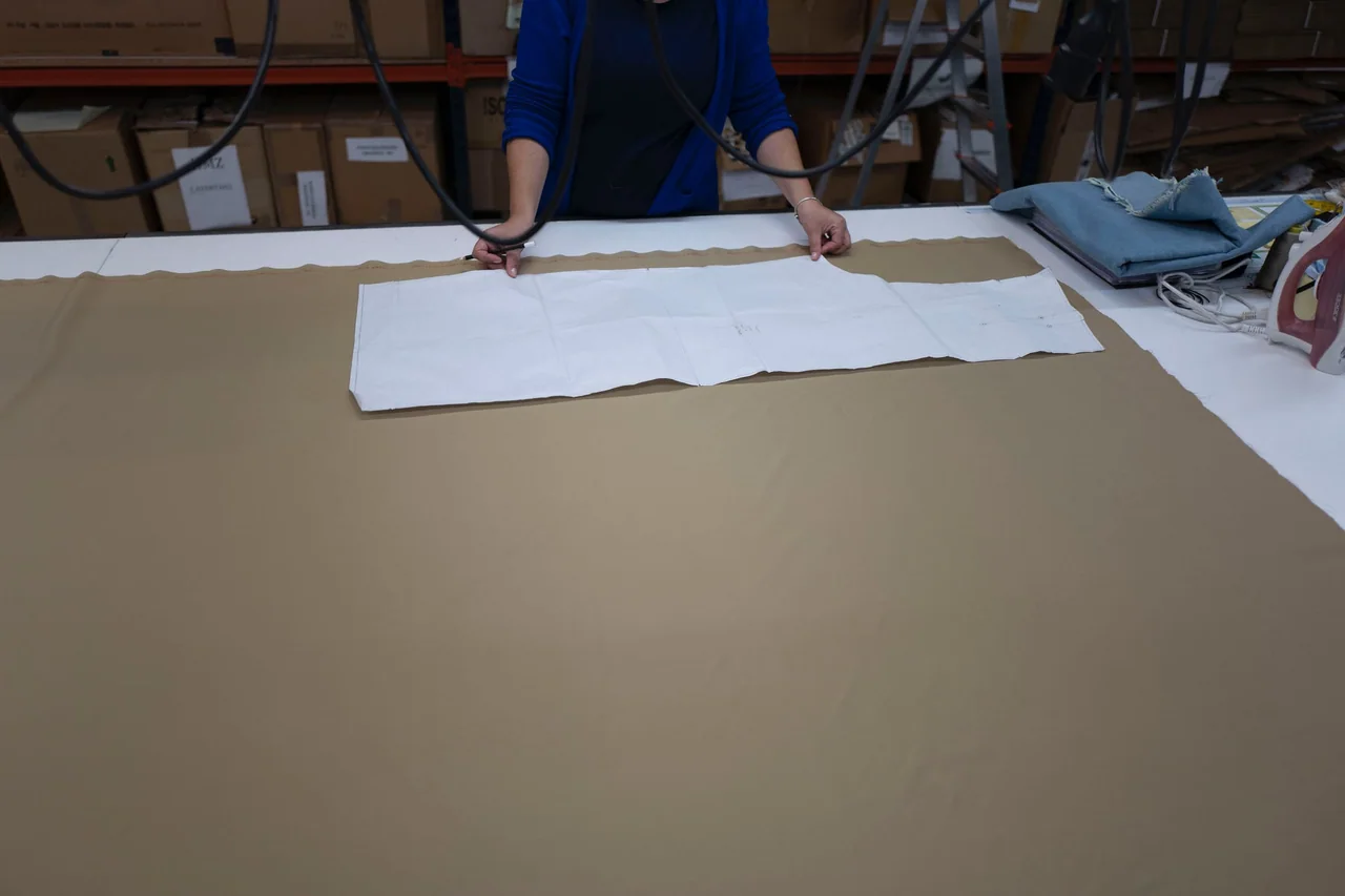 Une personne place un patron papier sur une grande table de coupe.