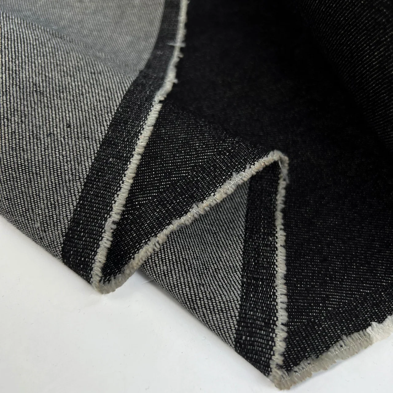 Black denim folded back to show contrasting face and reverse surfaces.
