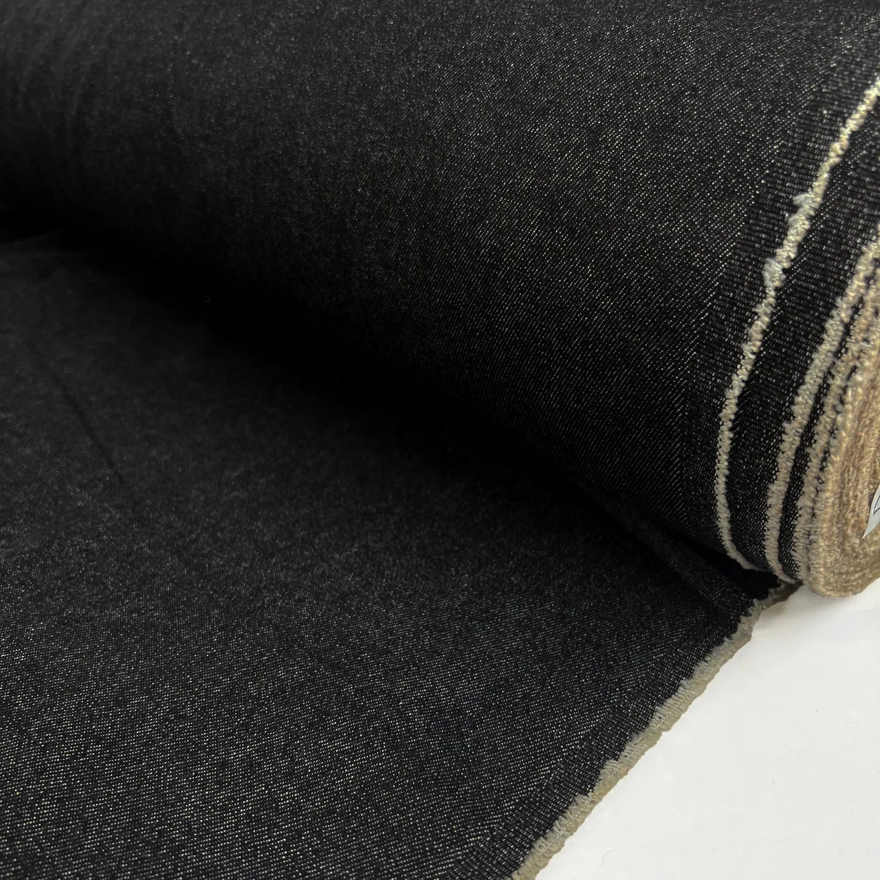Black denim with an exposed pale selvedge and diagonal weave.