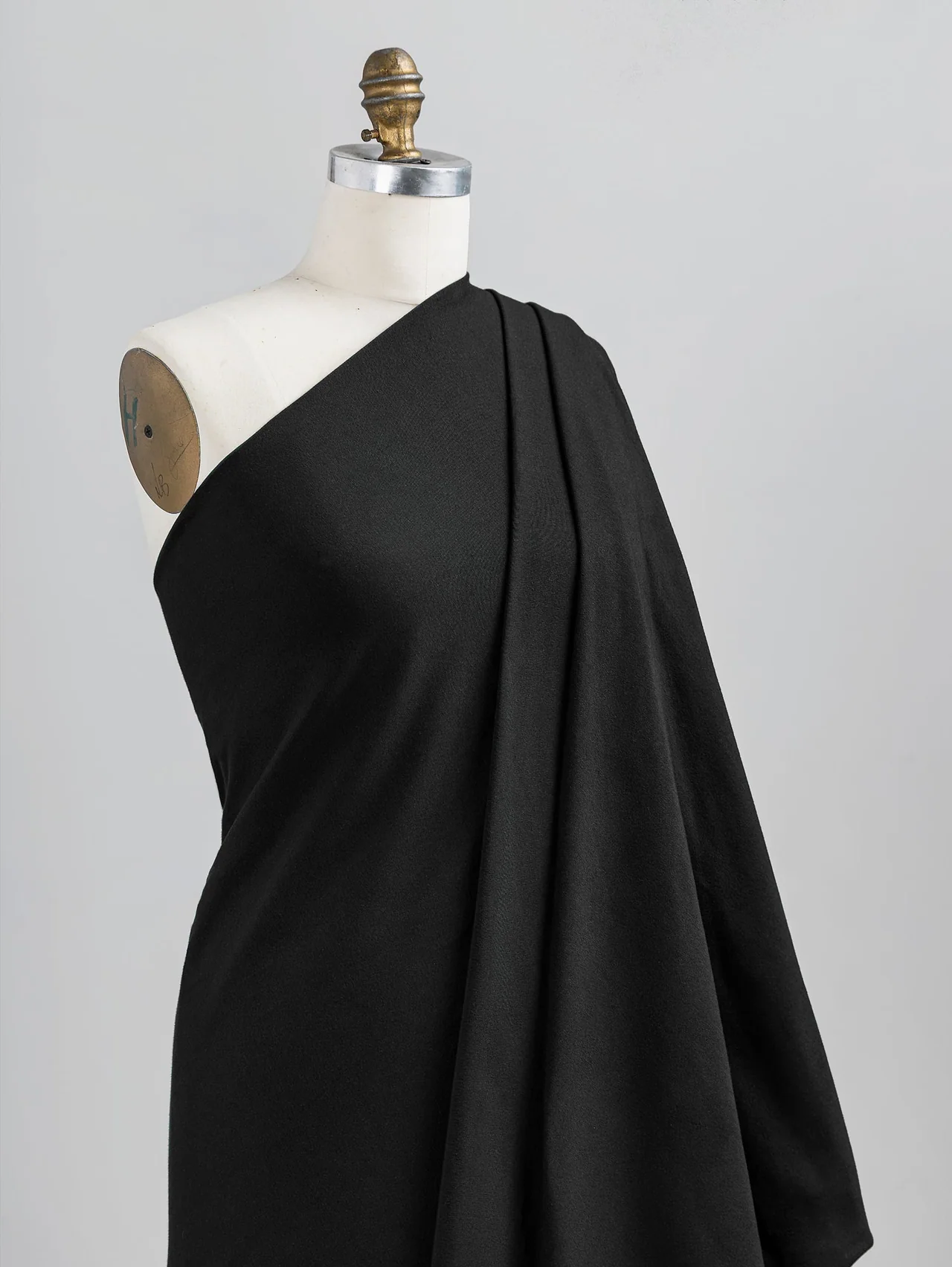 Un tissu noir extensible est drapé sur un mannequin pour étudier la silhouette.
