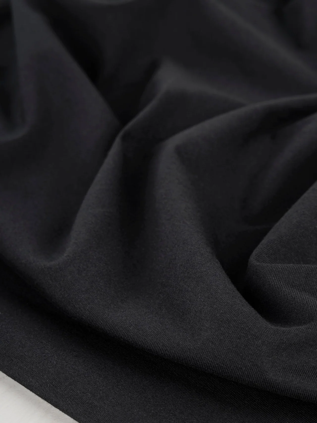 Black stretch jersey with folds showing its smooth surface.