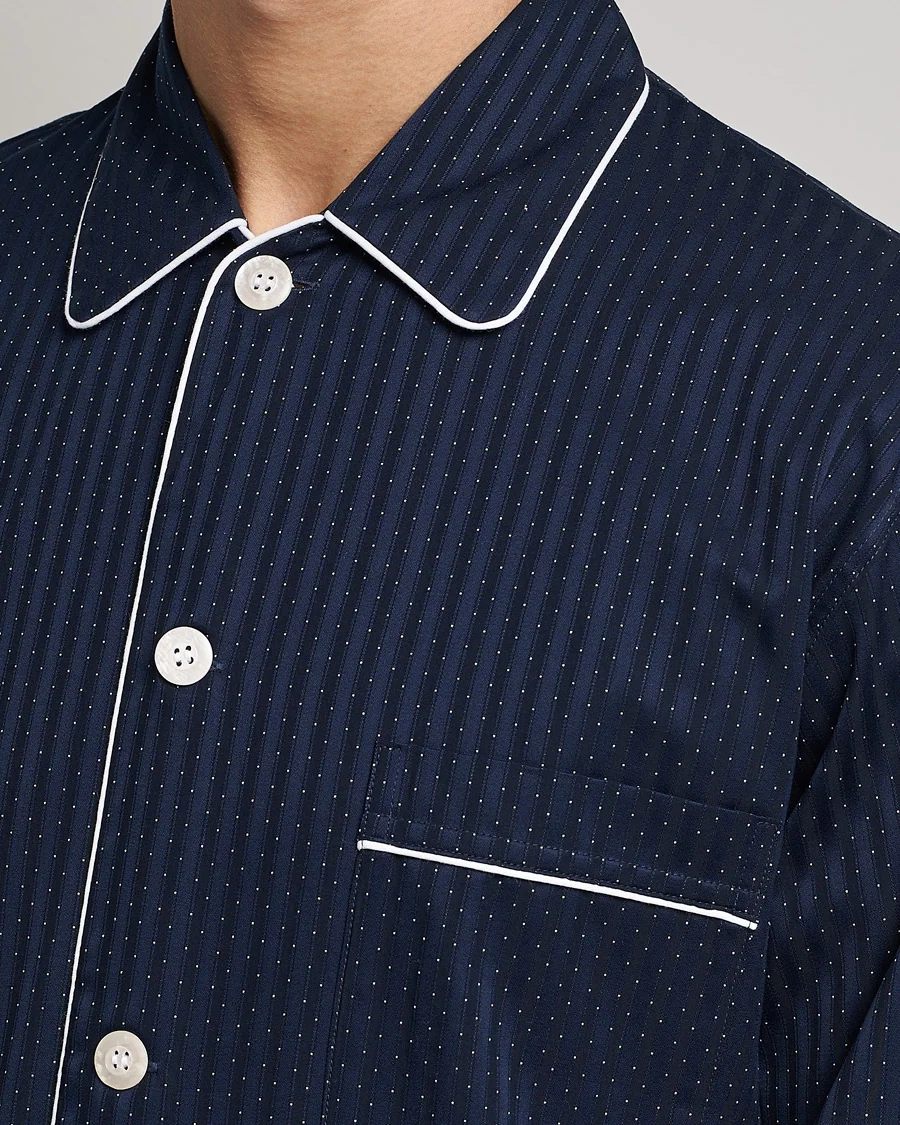Detalle de una camisa de pijama azul marino que muestra los vivos en contraste, los botones y el bolsillo del pecho.