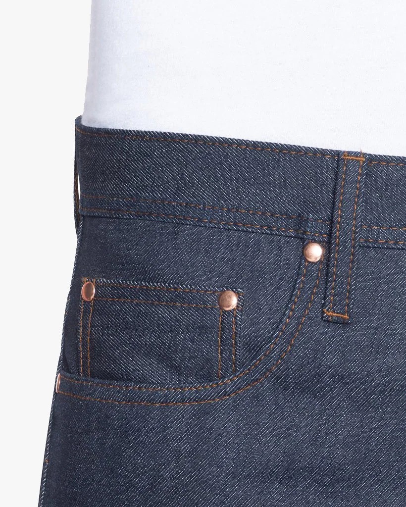 Close view of indigo jeans showing the waist, belt loop, copper rivets and pocket topstitching.