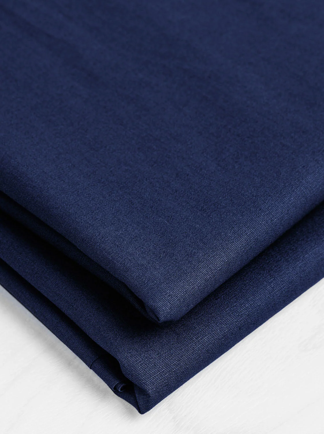 Deep navy cotton poplin folded to show its fine woven texture and clean drape.