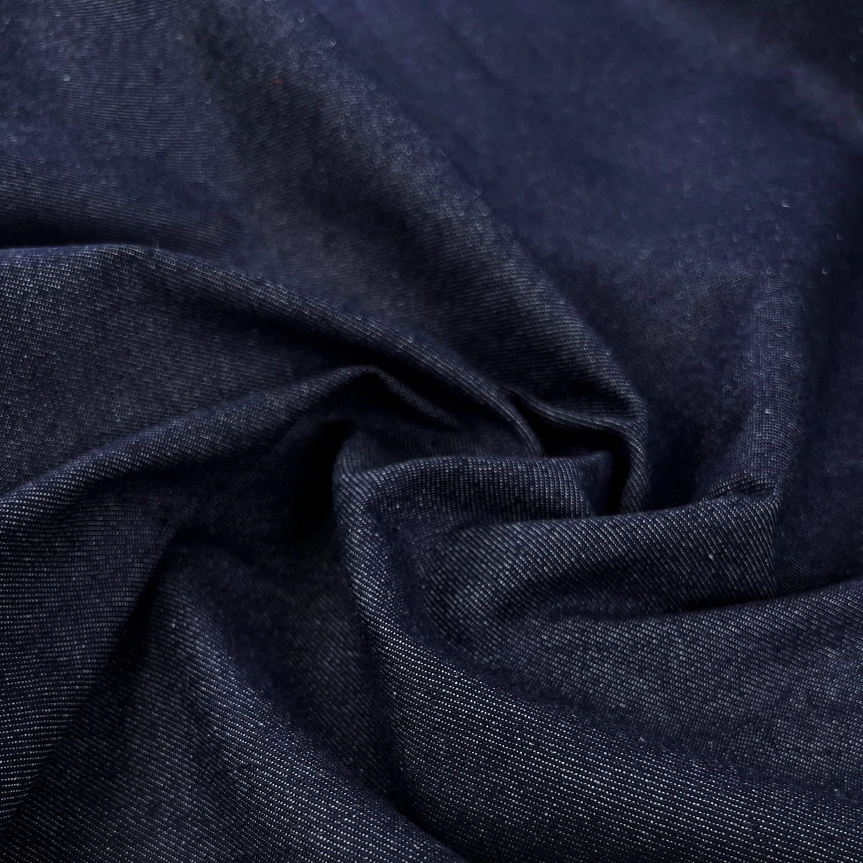 Indigo denim folded to reveal its diagonal twill weave and fabric weight.