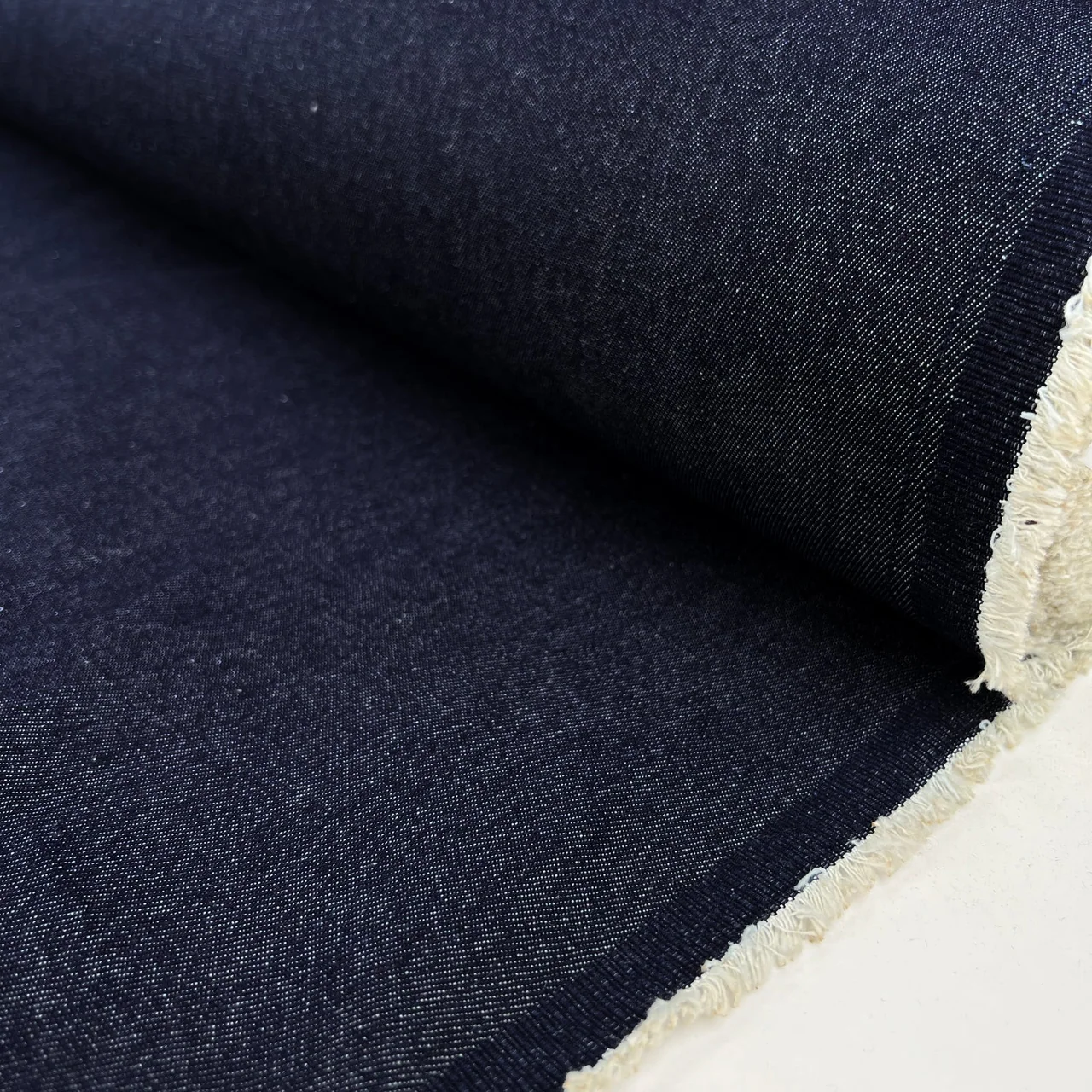 Indigo denim folds with a visible pale selvedge edge.