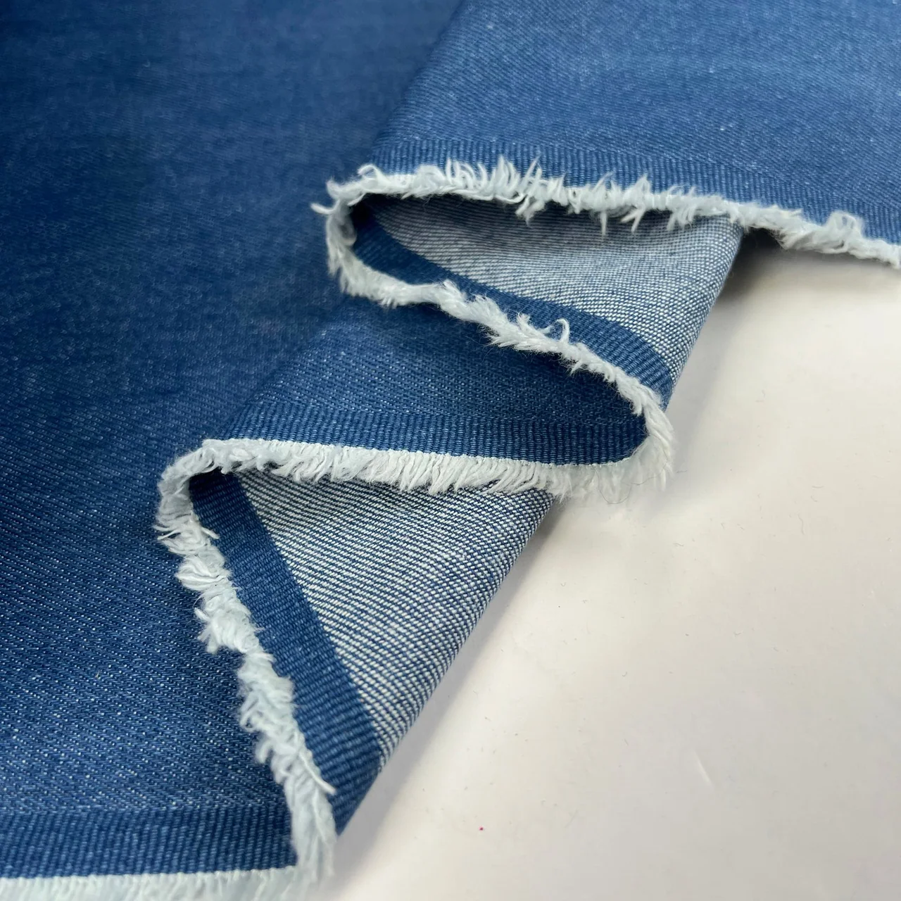 Mid-blue denim with a folded raw edge exposing the lighter reverse.
