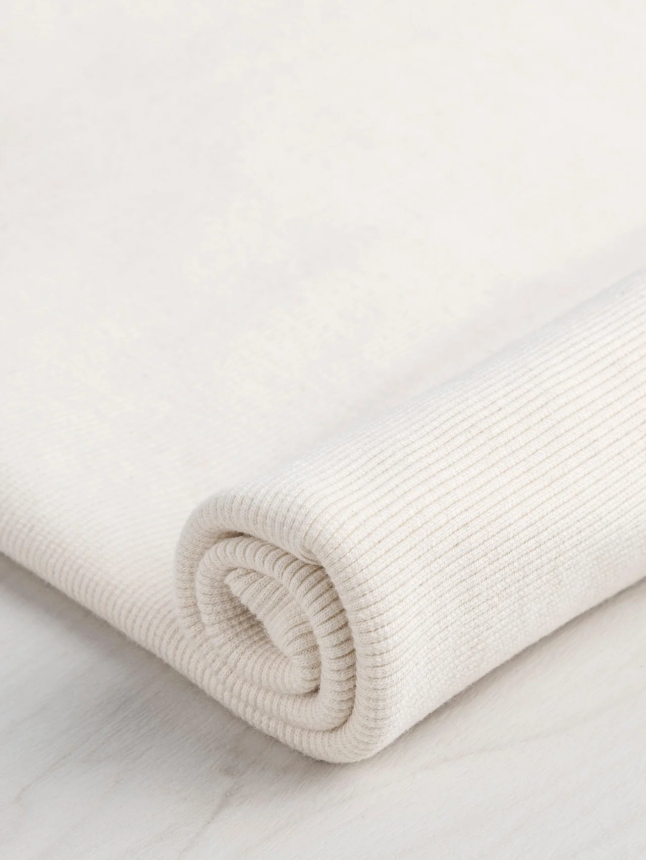 Natural rib knit rolled to reveal its parallel knitted columns.