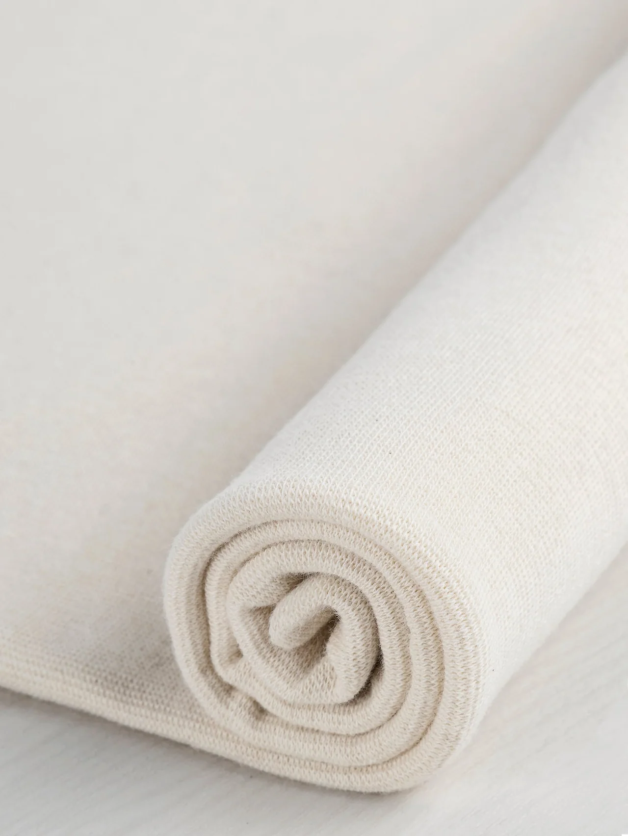 Natural rib knit rolled to show its edge and fine vertical structure.