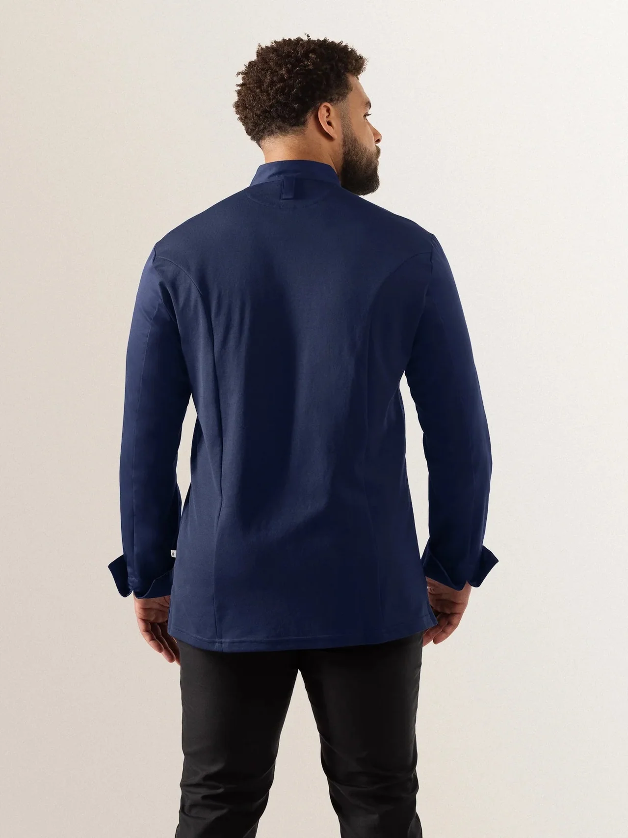Navy chef jacket worn from behind, showing the length and cuff shape.