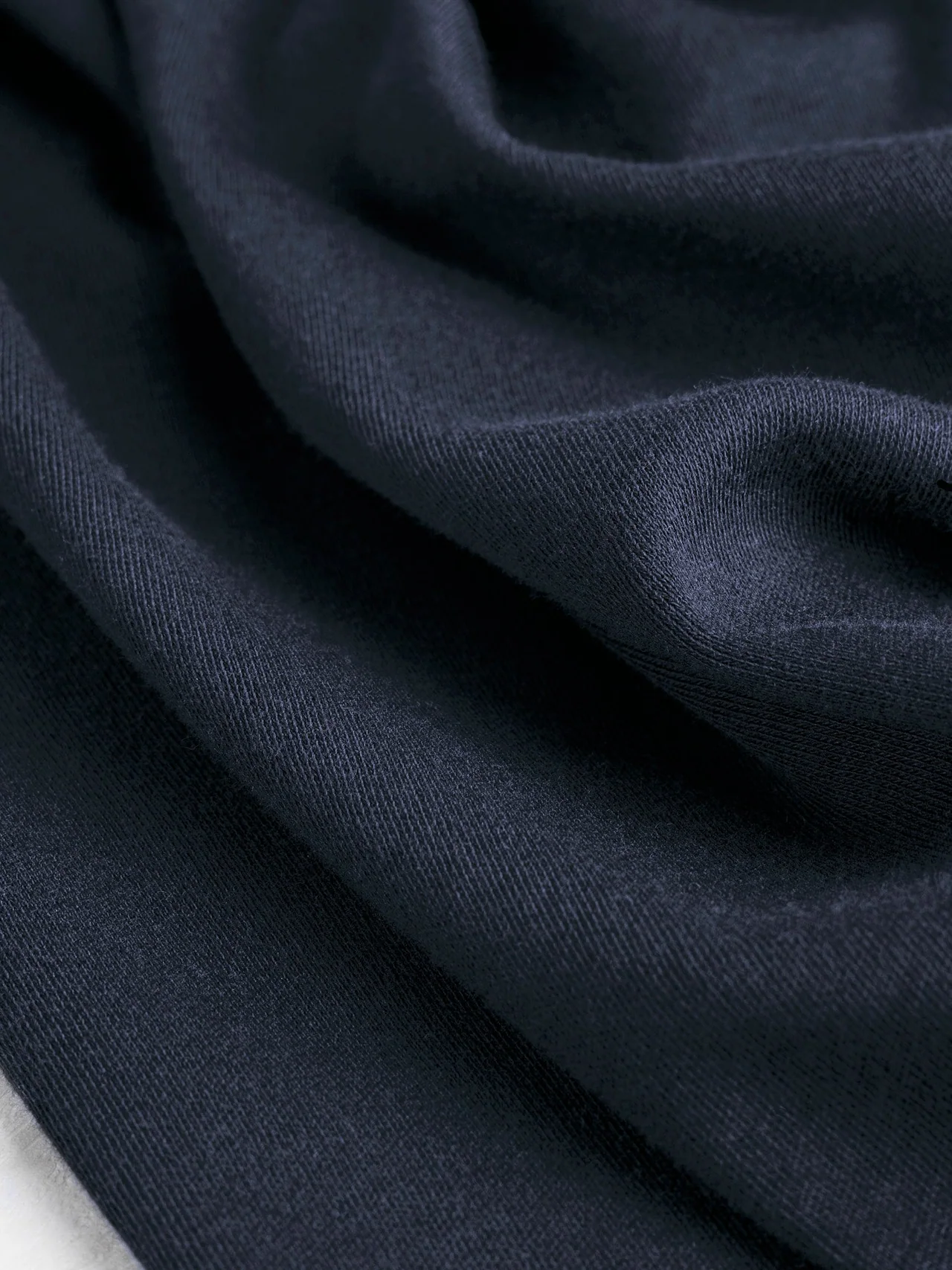 Navy jersey draped in folds to show a dense knitted surface.