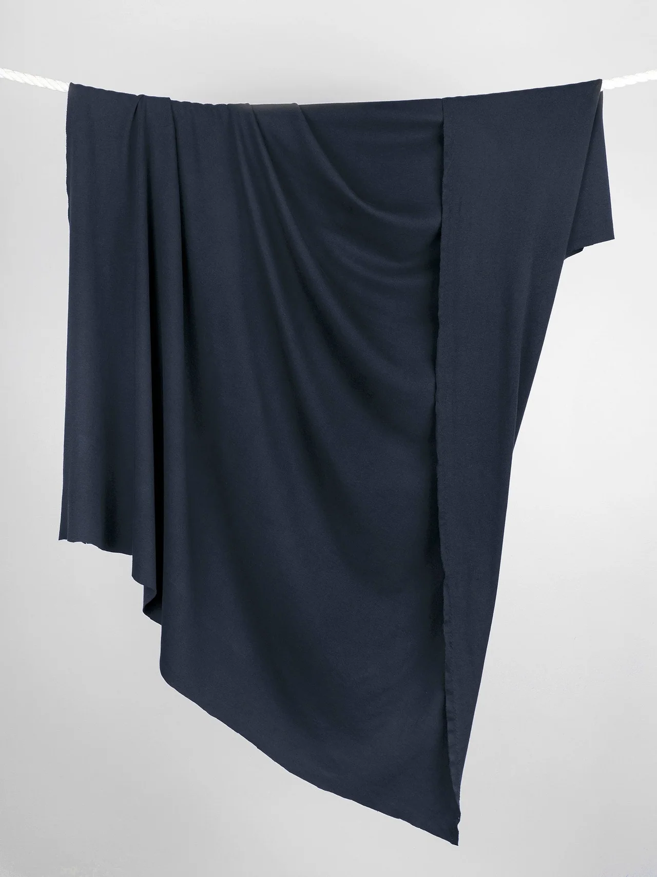 Navy jersey hanging freely to demonstrate its drape and weight.