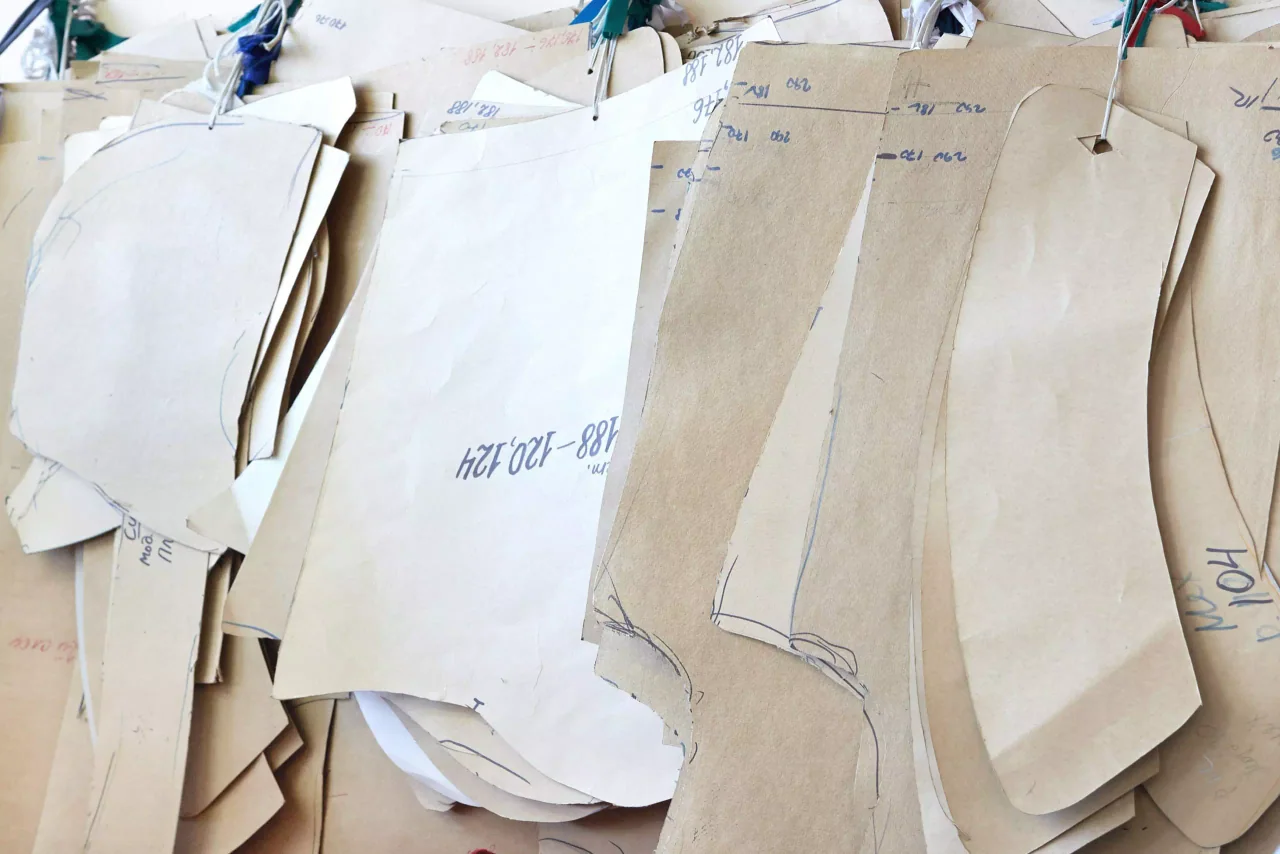 Des patrons papier portent des annotations de construction manuscrites.
