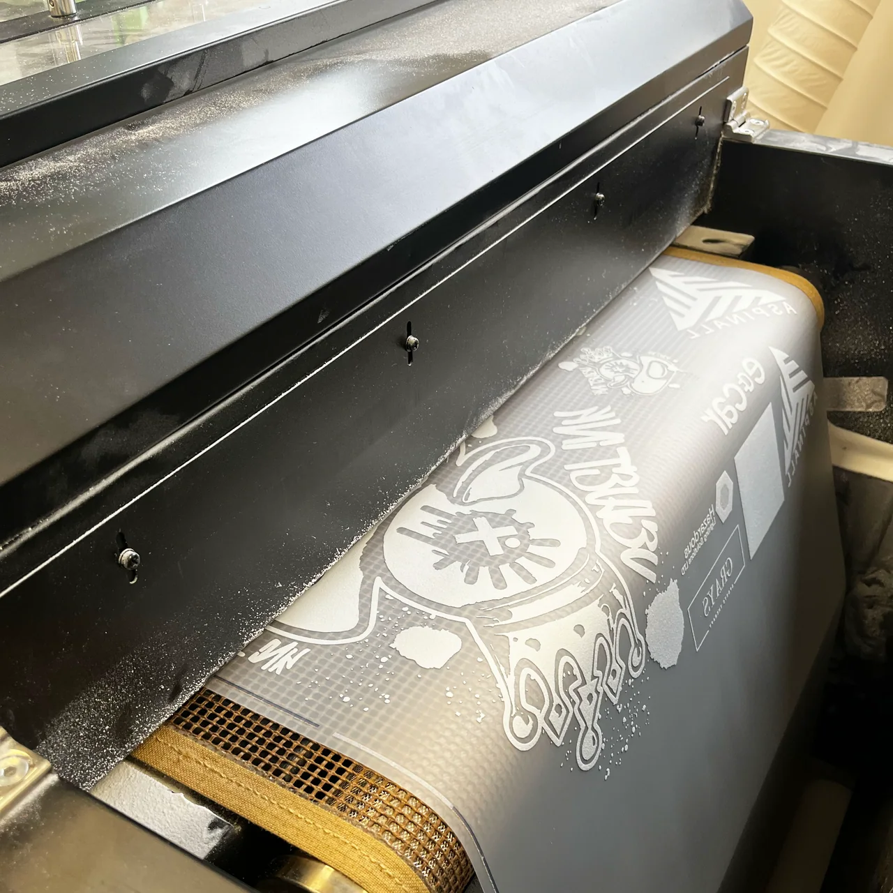 Printed transfer film passing through the rollers of a textile printing machine.
