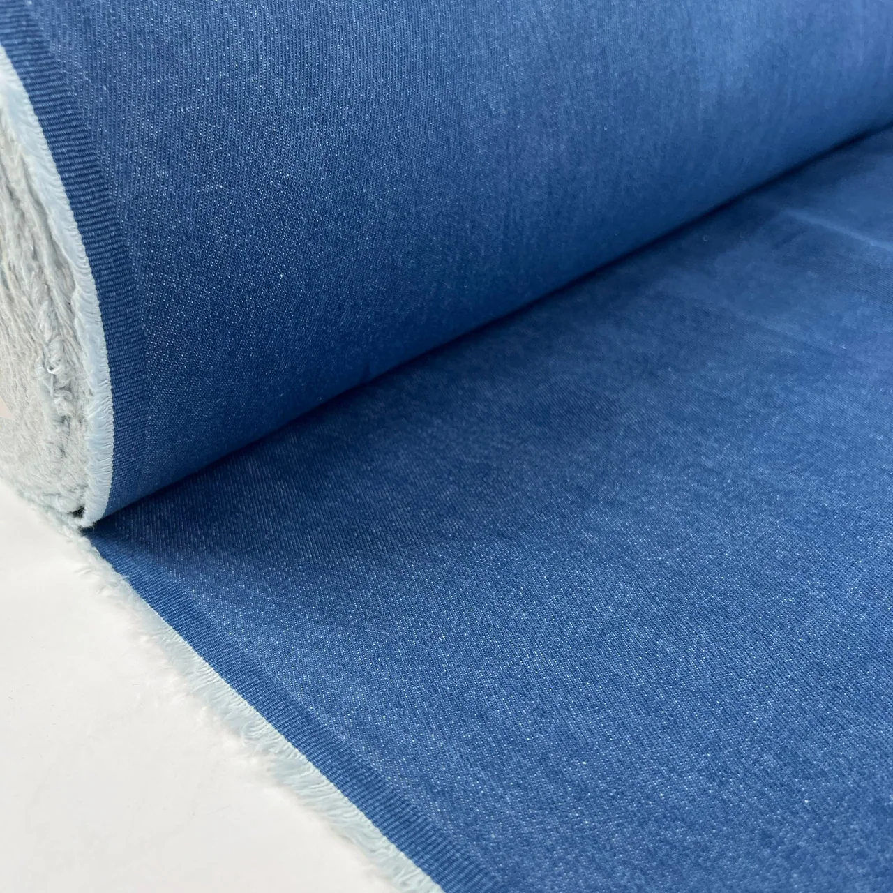 Roll of blue denim showing the fabric face and contrast woven reverse.